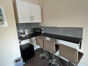a kitchen with a counter with chairs and a microwave at The New Brighton Hotel in New Brighton