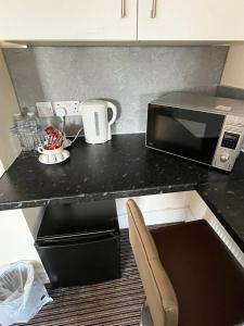 a kitchen with a counter with a microwave and a chair at The New Brighton Hotel in New Brighton