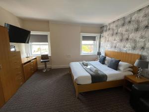 a bedroom with a bed and a dresser and two windows at The New Brighton Hotel in New Brighton