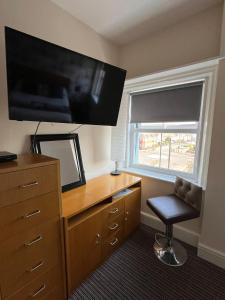 a bedroom with a dresser with a television and a chair at The New Brighton Hotel in New Brighton
