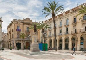 a man walking in front of a building with palm trees at NICE CENTRIC APARTMENT in Vilanova i la Geltrú