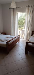 a bedroom with two beds and a large window at El Doro Rooms in Dhërmi