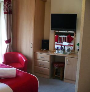 a hotel room with a desk with a tv on it at Milverton House in Llandudno