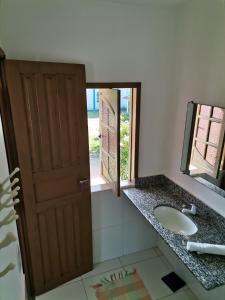 a bathroom with a sink and a mirror and a door at Hospedaria Cosanostra in Itaúnas