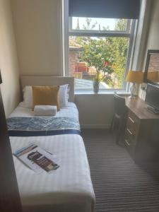 a bedroom with a bed and a desk and a window at The New Brighton Hotel in New Brighton