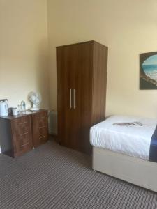 a bedroom with a bed and a wooden cabinet at The New Brighton Hotel in New Brighton
