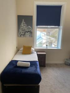 a bedroom with a bed with a blue blanket and a window at The New Brighton Hotel in New Brighton