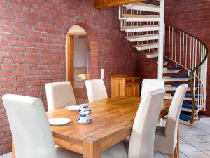 ein Esszimmer mit einer Ziegelwand, einem Holztisch und Stühlen in der Unterkunft Holiday Home Riedehuus by Interhome in Norddeich