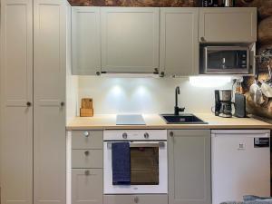 eine Küche mit weißen Schränken und einem Herd mit Backofen in der Unterkunft Holiday Home Keloveska by Interhome in Ruka