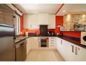 a kitchen with white cabinets and red walls at Apartment Penthouse Las Palmeras by Interhome in Cala Romantica