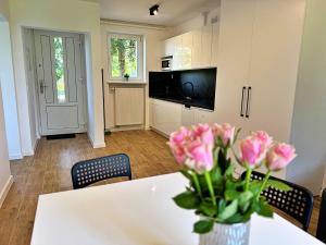 a kitchen with a table with a vase of pink roses at Apartamenty Lotnisko Leszno in Leszno