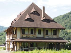 a large house with a gambrel roof at Pensiunea Sanziene in Strîmtura