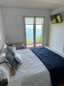 a bedroom with a large bed with a large window at PIPER ETXEA. Relax, mar y monte! in Mutriku