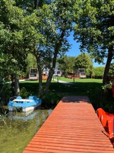 a boat sitting on the water next to a dock at Apartamenty Zielona Dolina nr 2 in Szteklin +6 photos