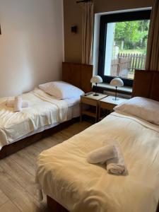 two beds in a room with a window at Apartamenty Zielona Dolina nr 2 in Szteklin