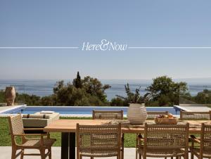 a wooden table with chairs and a table with a bowl of fruit at Cicada Exclusive Villa, a Sea View Gem, By ThinkVilla in Akrotiri
