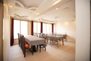 a dining room with tables and chairs and windows at Green orchard skardu in Skardu
