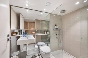 a bathroom with a toilet and a sink and a shower at Pacific Chic Luxury Pad - Beachfront Aircon Lift in Sydney