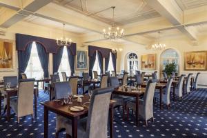 a dining room with tables and chairs and chandeliers at The Palace Hotel in Paignton