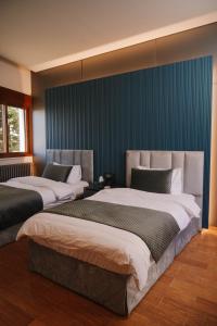 two beds in a room with blue walls at Hotel Ehden in Ehden