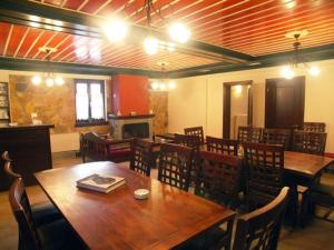 um restaurante com mesas e cadeiras de madeira e uma lareira em Zagori Philoxenia Hotel em Monodendri