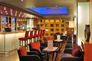 a restaurant with a bar with red chairs and a counter at Verdi Budapest Aquincum in Budapest