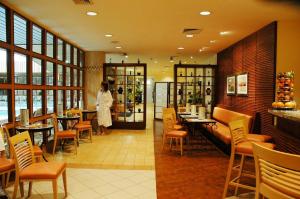 a restaurant with a woman standing in a room with tables and chairs at Verdi Budapest Aquincum in Budapest