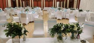 a room filled with white tables and chairs with flowers at Verdi Budapest Aquincum in Budapest