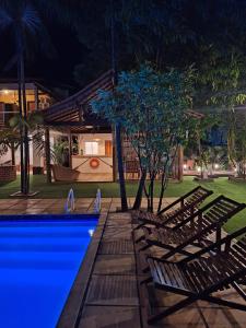 a group of chairs next to a swimming pool at night at Babylon Village in Algodoal