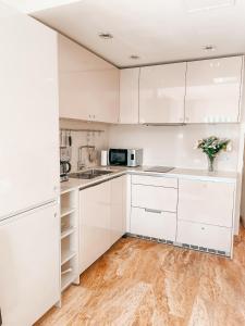 a white kitchen with white cabinets and a wooden floor at Cosy flat with sea view, pool and terrace in Altamira-complex in Costa Adeje - Playa del Duque in Adeje +45 photos