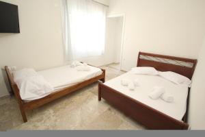 two beds in a room with a window at Nikolas Marios by Frangki in Agia Marina Aegina