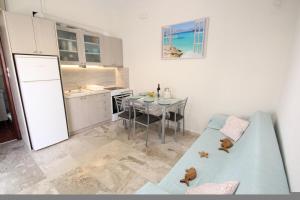 a kitchen with a table and a blue couch in a room at Nikolas Marios by Frangki in Agia Marina Aegina