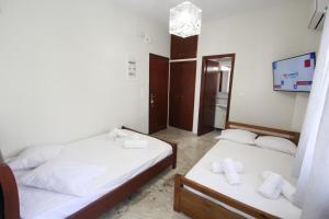 a room with two beds and a tv in it at Nikolas Marios by Frangki in Agia Marina Aegina