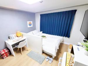 a bedroom with a bed and a desk and a blue curtain at The Stay 132 in Uijeongbu