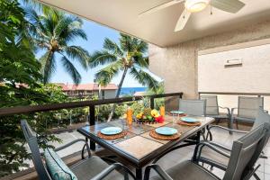 Una mesa y sillas en un balcón con palmeras. en Kona Pacific D622, en Kailua-Kona