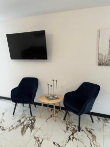 two chairs and a table with a tv on a wall at Apartamenty Zielona Dolina nr 4 in Szteklin