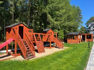 a playground with wooden play equipment in the grass at Apartamenty Zielona Dolina nr 3 in Szteklin