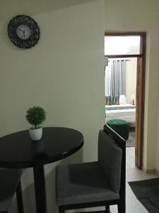 a dining room table and a chair with a clock on the wall at Ashley's apartment in Bamburi +3 photos