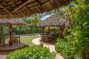 eine Terrasse mit Tischen und Stühlen im Garten in der Unterkunft Maisha Nungwi - Boutique Hotel in Nungwi