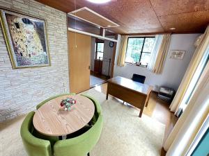 a living room with a wooden table and green chairs at うぐいすハウス in Henoiri