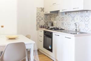 a white kitchen with a sink and a stove at Serra Cozy Apartments in Centola +3 photos