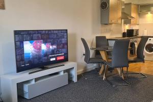 Il comprend un salon doté d'une télévision et d'une table avec des chaises. dans l'établissement Large 2 bed flat in Bolton, à Farnworth