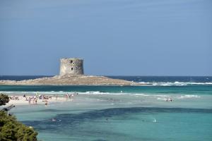 a group of people on a beach with a castle at UNAHOTELS Club Hotel Ancora in Stintino