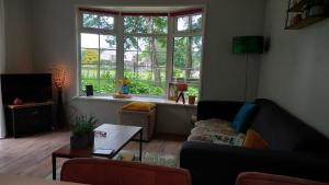 a living room with a couch and a table and a window at Woudthuisje in Laag-Soeren