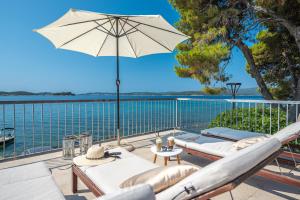 a patio with chairs and an umbrella and the water at Beachvilla AdriaStone with Pool and Jacuzzi in Orebić