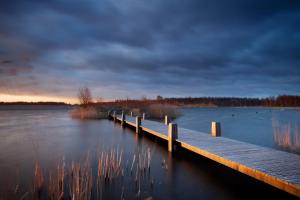 a dock on a lake with a cloudy sky at Casa Belvedere in Göhren-Lebbin