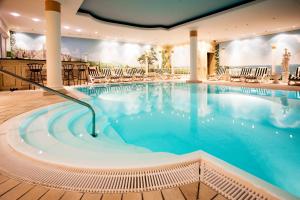 a large swimming pool in a hotel with chairs at Atrium Hotel Krüger in Rostock