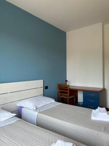two beds in a room with a desk and a desk at B&B Gioia in Salsomaggiore Terme