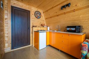 a kitchen with an orange door in a wooden room at Cozy House Gulebi in K'eda
