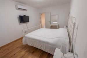 a white bedroom with a bed and a tv at La Casetta in Comacchio